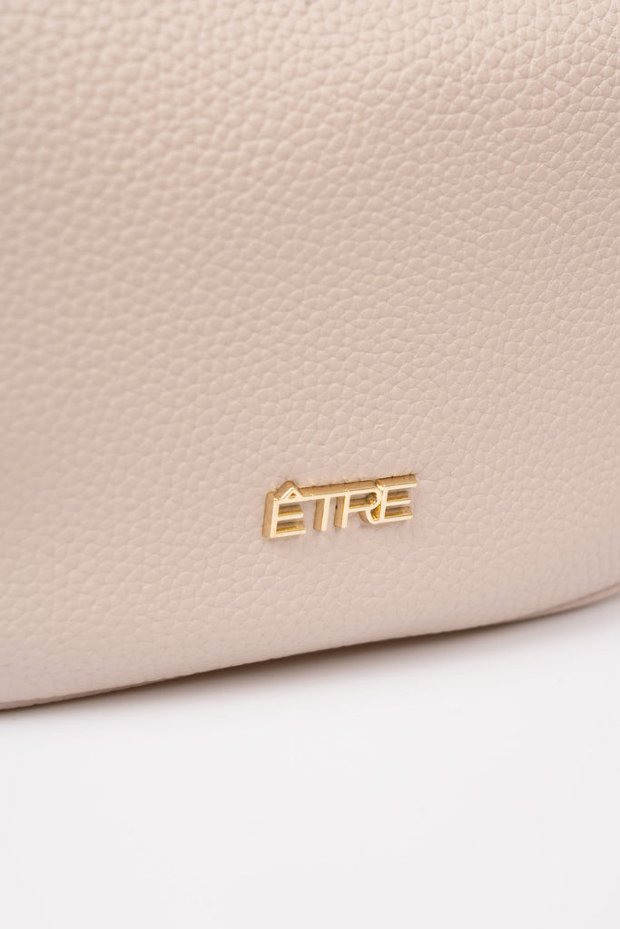 stevie-half-moon-crossbody-bag-nude-pebbled-faux-leather-close-up-logo
