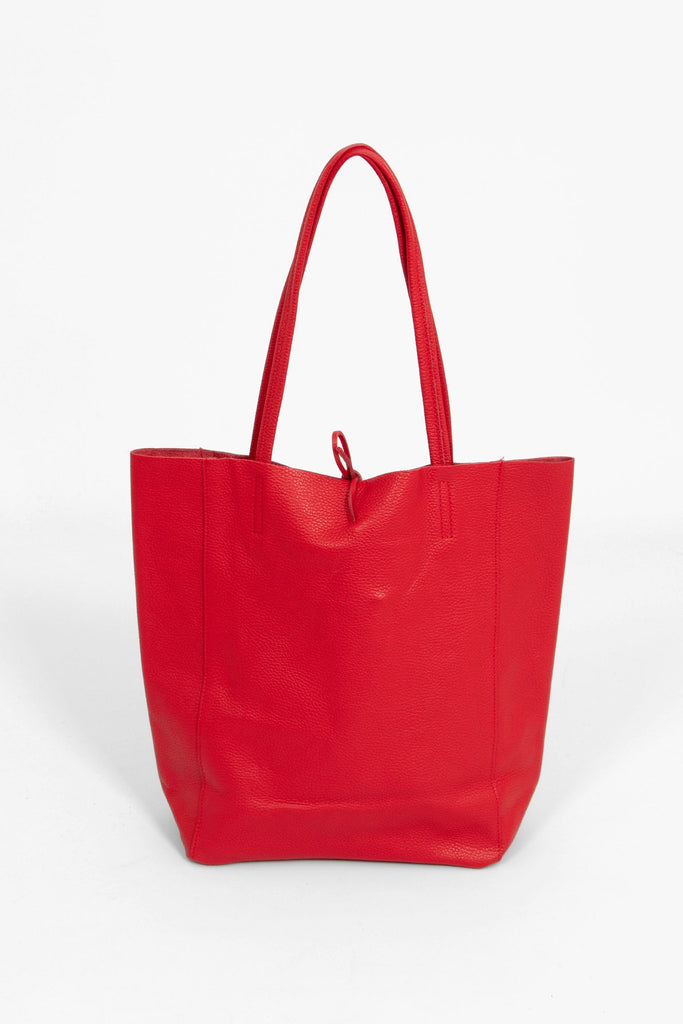 the red leather tote bag is standing upright, this images shows the back of the bag which is plain red.