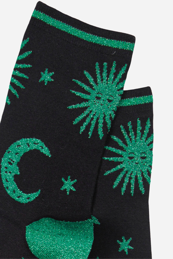 close up of the green glitter sun and moon pattern on the black bamboo socks