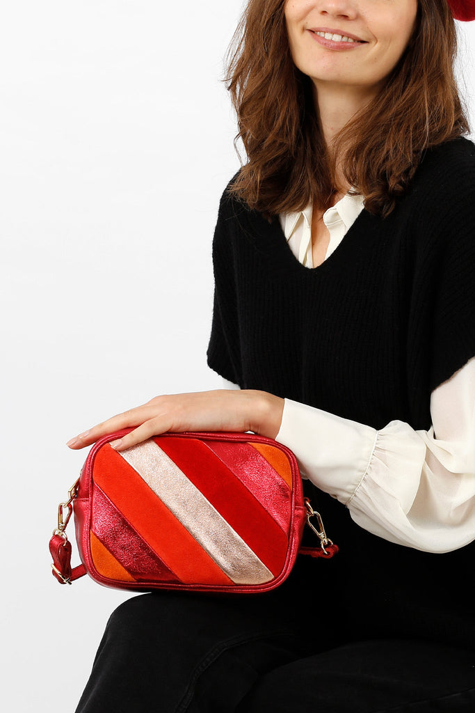 model holding the red striped crossbody camera bag showing the size of the bag