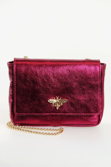 magenta pink leather cross body bag with a gold chain strap and a gold bee clasp on the front