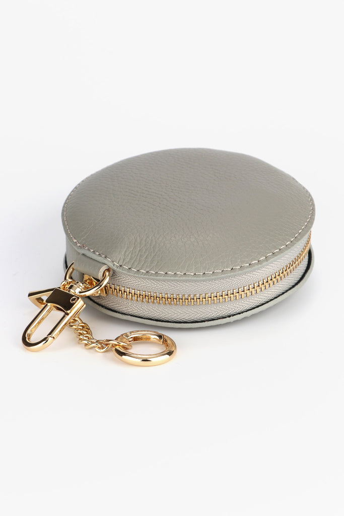 light grey round leather coin purse with a secure zip closure and gold hardware