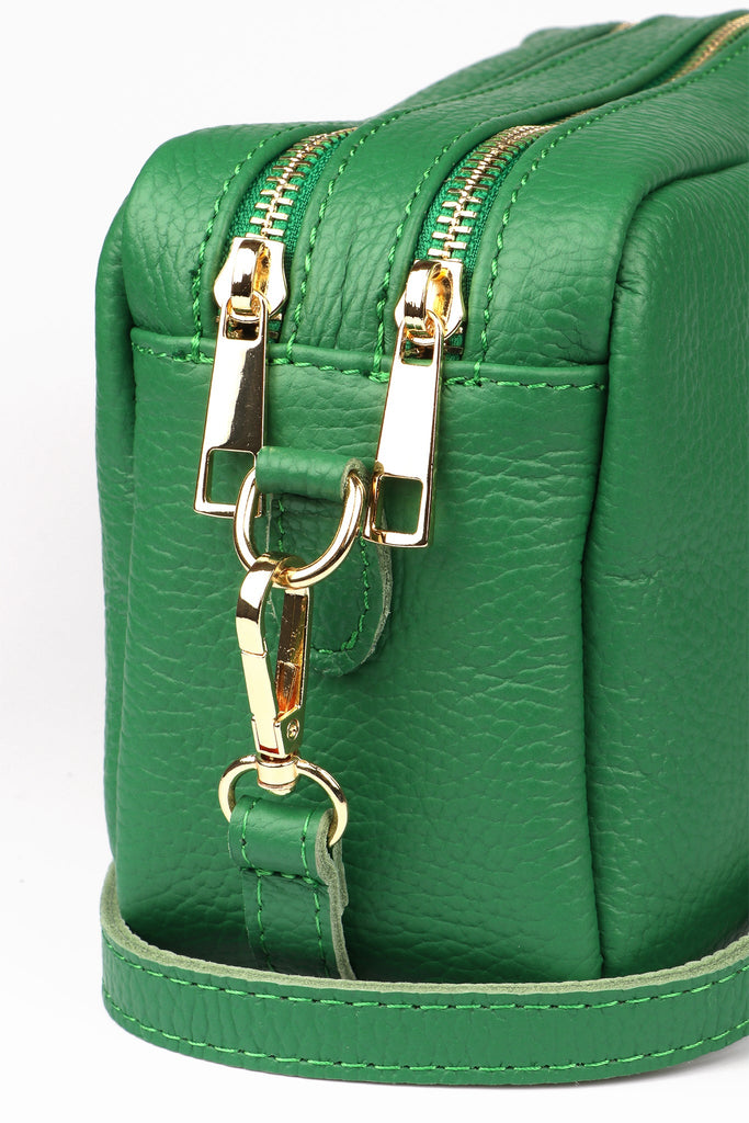 close up of the dual zip closing compartments on the green leather camera bag