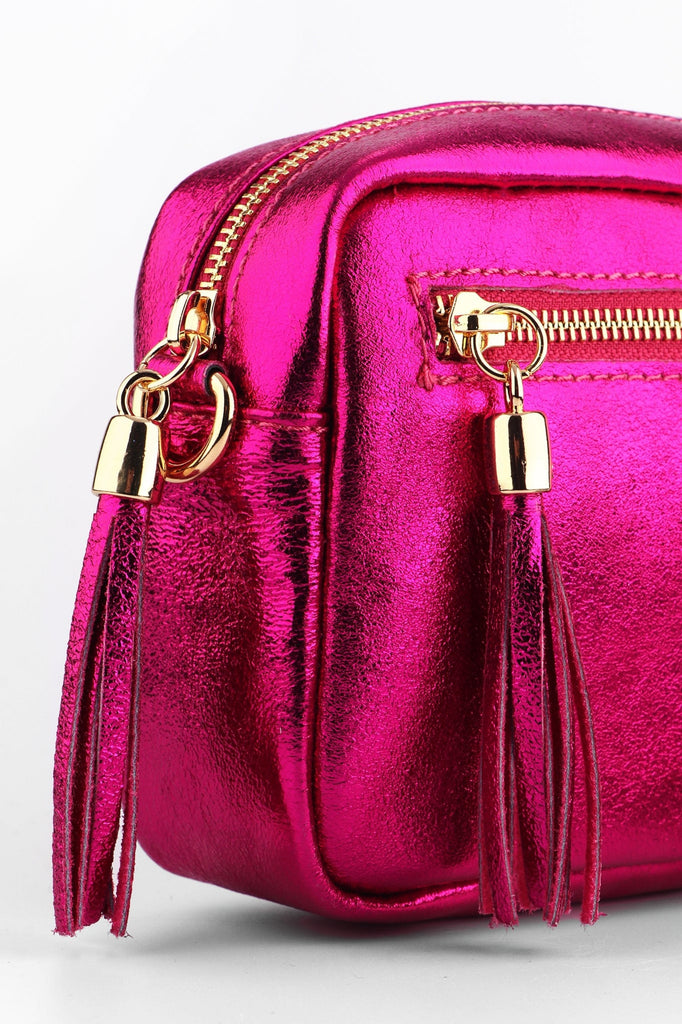 close up of the vibrant pink metallic leather and tassles on the small camera bag