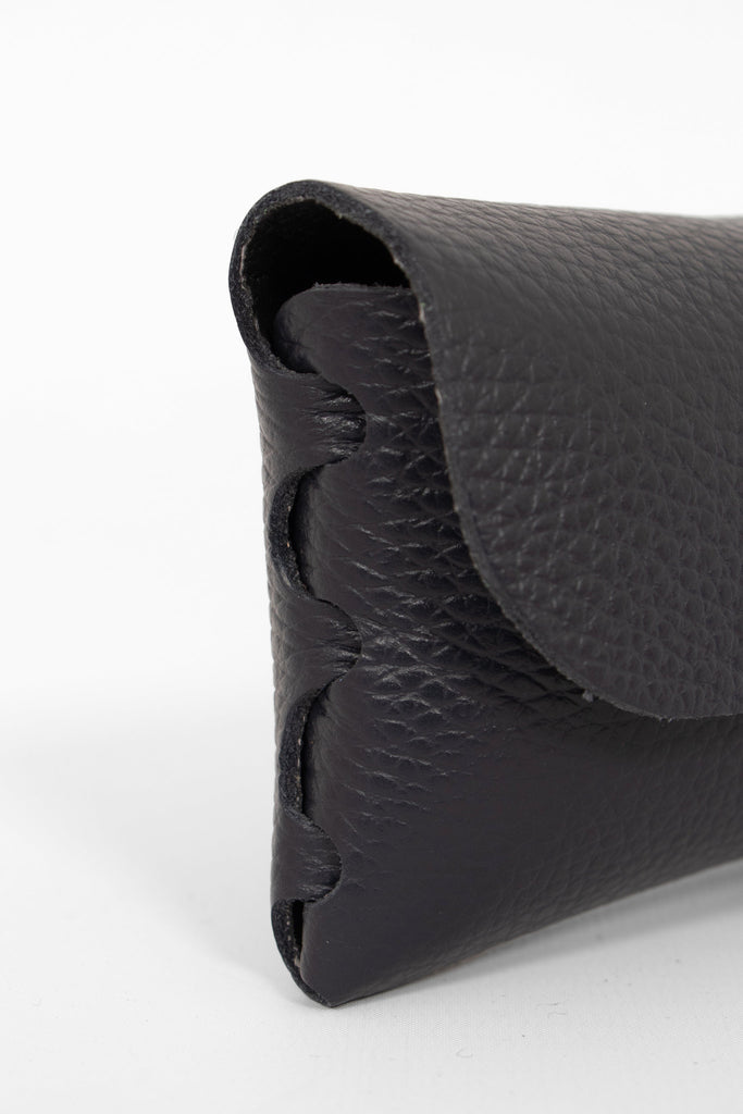 close up of the side view of the sunglasses case, showing the structure of the design. the case has a folding front which is secured by a button fastening