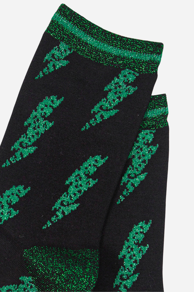 close up of the green glitter lightning bolt pattern on the black bamboo socks