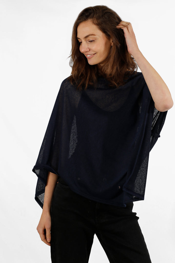 model wearing a plain navy blue lightweight poncho with an asymmetrical hemline and short wide sleeves