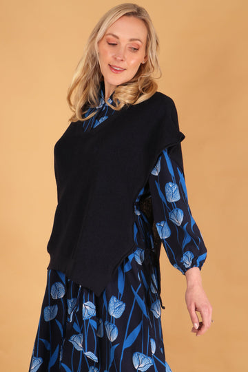 model wearing a navy blue knitted tank top over a blue floral dress to show that if can be worn as a layer