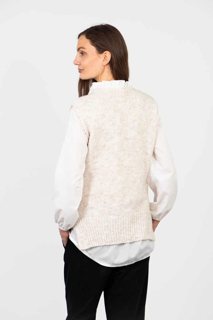 model showing the back of the knitted vest top, it is plain cream and has a round neck at the back