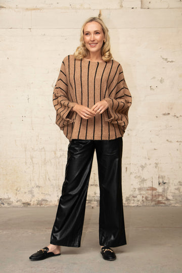 model wearing an oversized beige knitted jumper with vertical black stripes and a boat neck