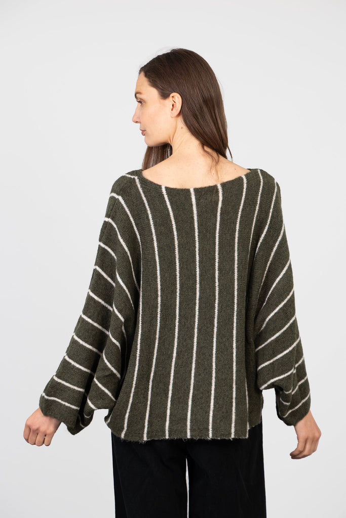 model wearing an oversized khaki green knitted jumper with vertical cream stripes and a boat neck