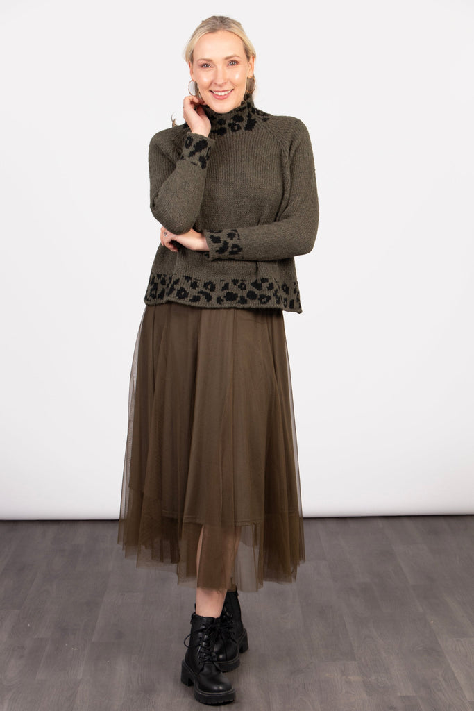 model wearing a khaki green tulle skirt paired with black ankle boots and a green leopard print jumper. the skirt is midi length and has an elasticated waist