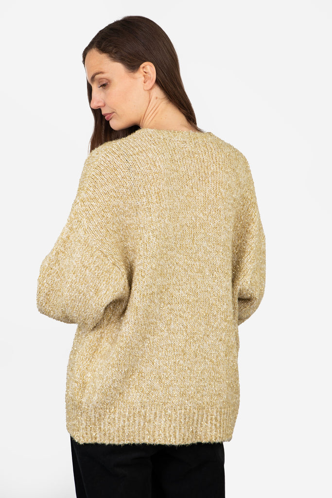 model showing the back of the gold sparkly cardigan, showing an all over sparkly material