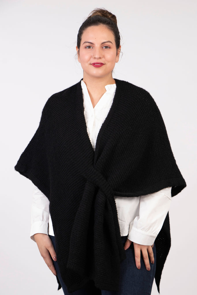 model wearing a plain black knitted tuck through sleeveless wrap poncho