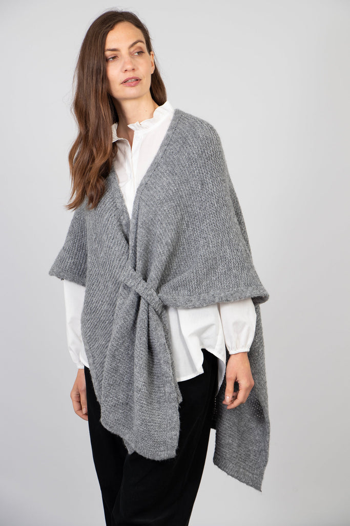 model wearing a grey knitted tuck through wrap with a v-neck and asymmetric hem