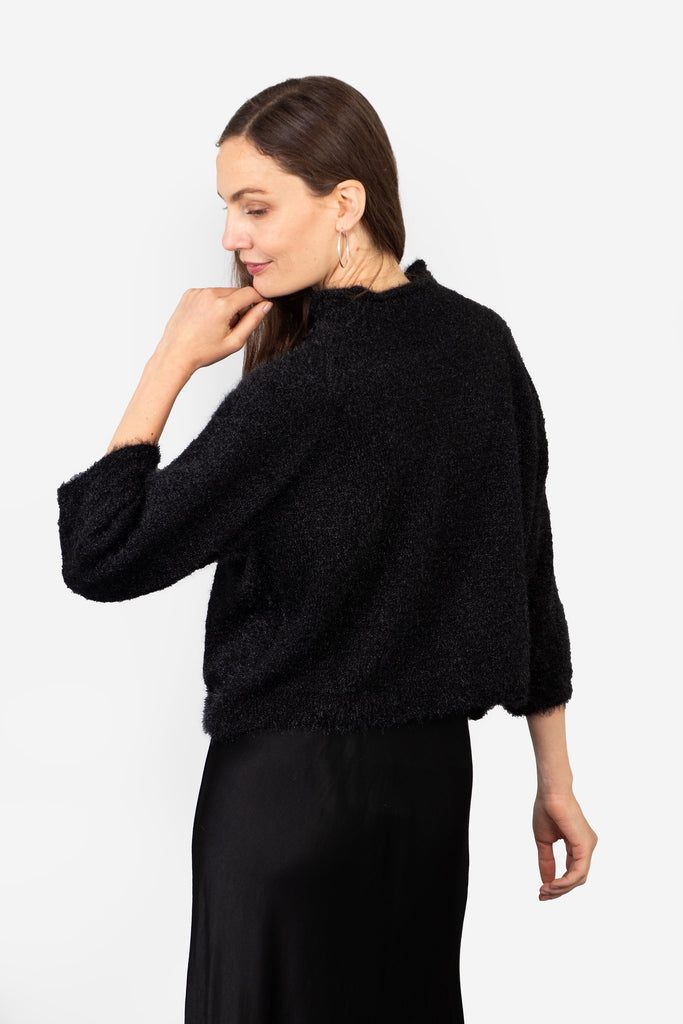 model showing the back of the jumper, the neck is high at the back and the design is plain