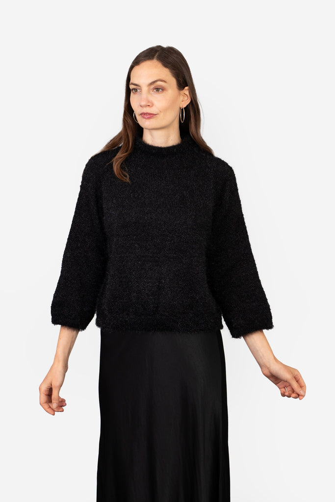 model showing the back of the jumper, the neck is high at the back and the design is plain