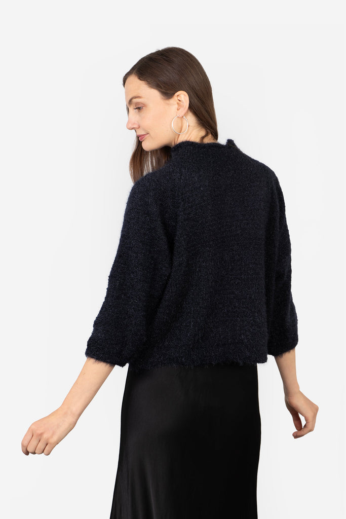 model showing the back of the jumper, the neck is high at the back and the design is plain