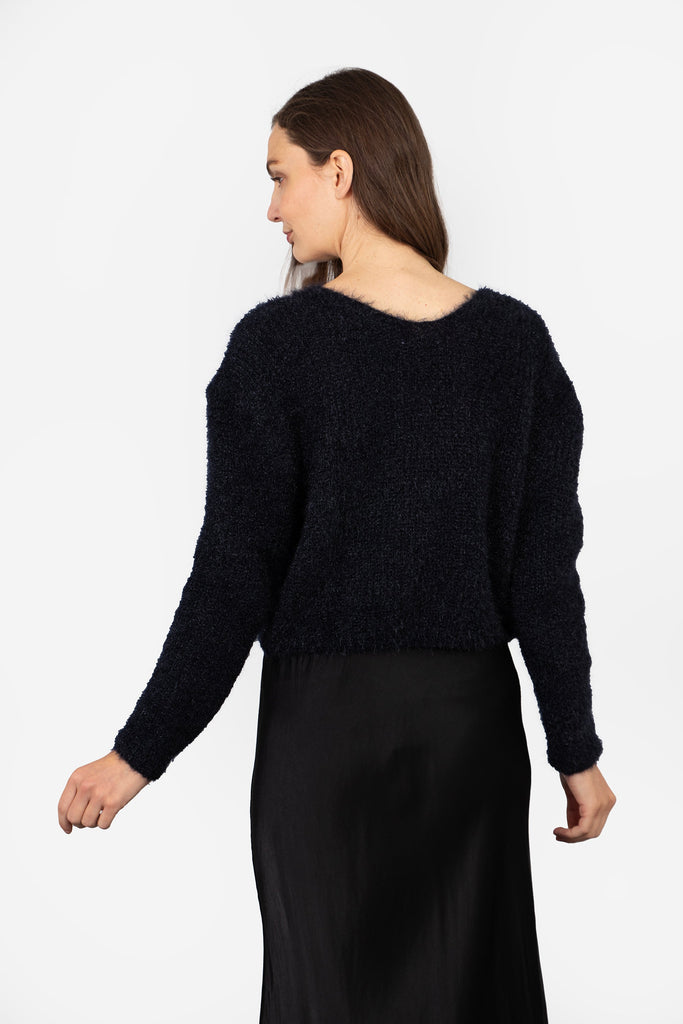 model showing the back of the cardigan, it is plain navy blue and has a round neck