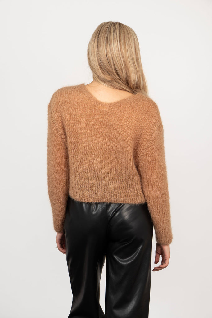model showing the back of the cardigan, is is plain tan coloured