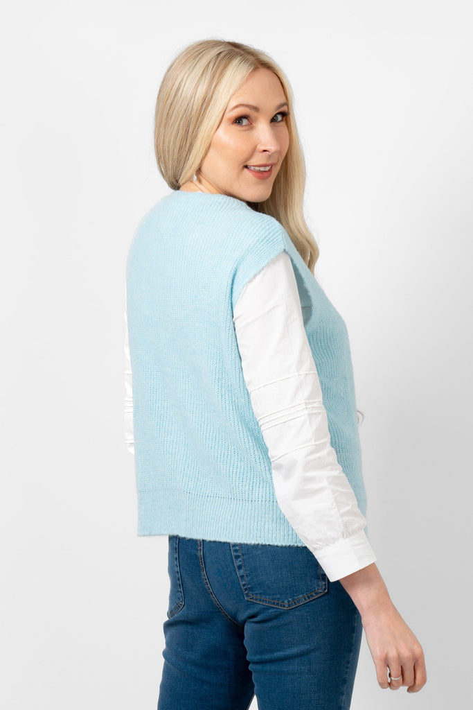 light blue knitted sleeveless tank top shown on a model and photographed from the rear. showing clearly the sleeveless design of this knitwear.