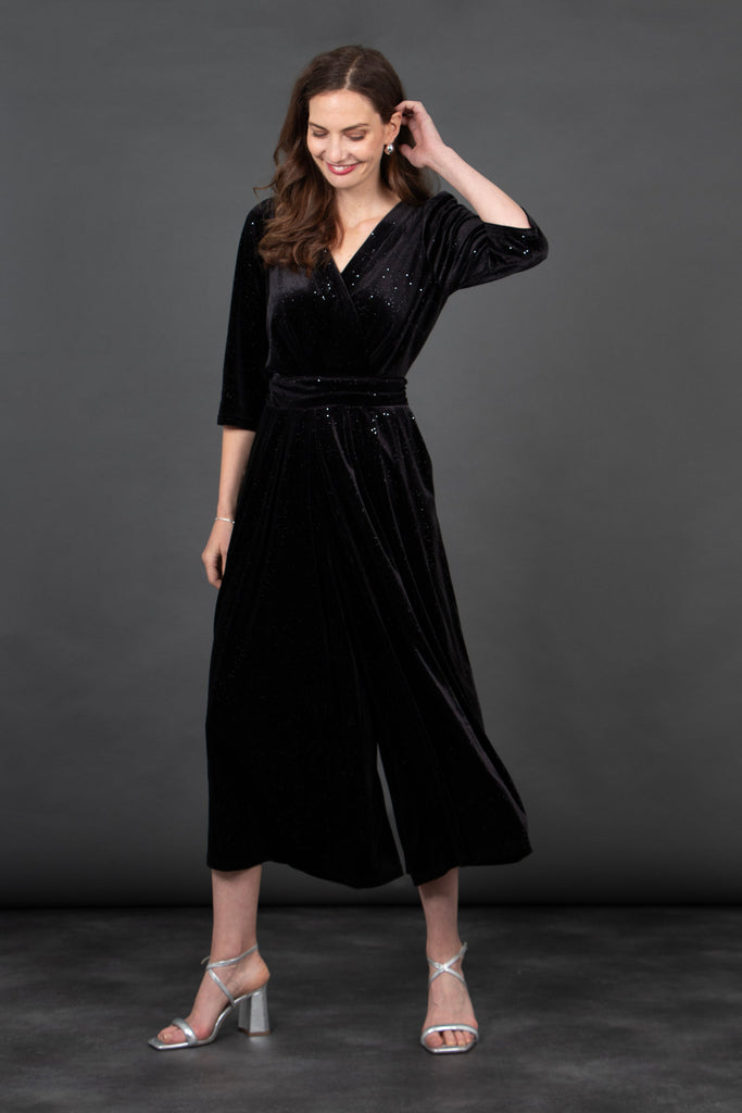 model wearing a cropped black velvet jumpsuit, the jumpsuit has an all over silver sparkle, v-neck and tie waist