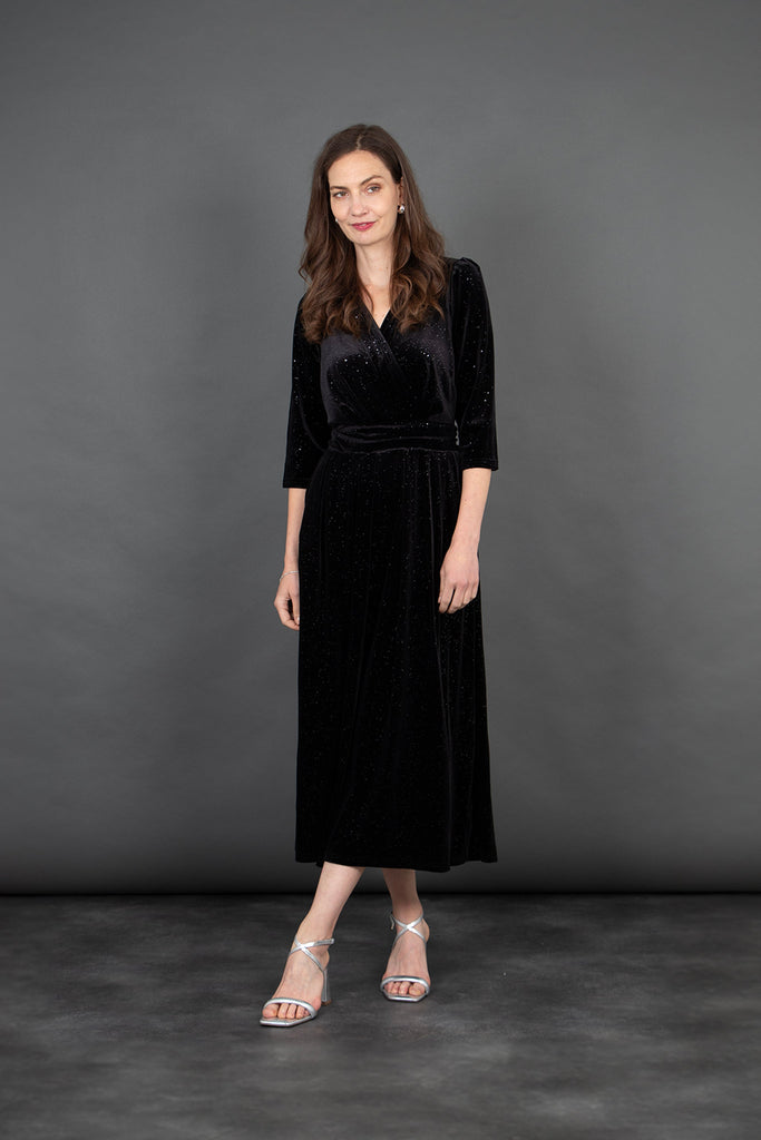 model wearing a black velvet jumpsuit, with 3/4 sleeves and a subtle glitter sparkle