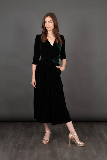 model wearing a cropped green velvet jumpsuit with a v-neck and pockets