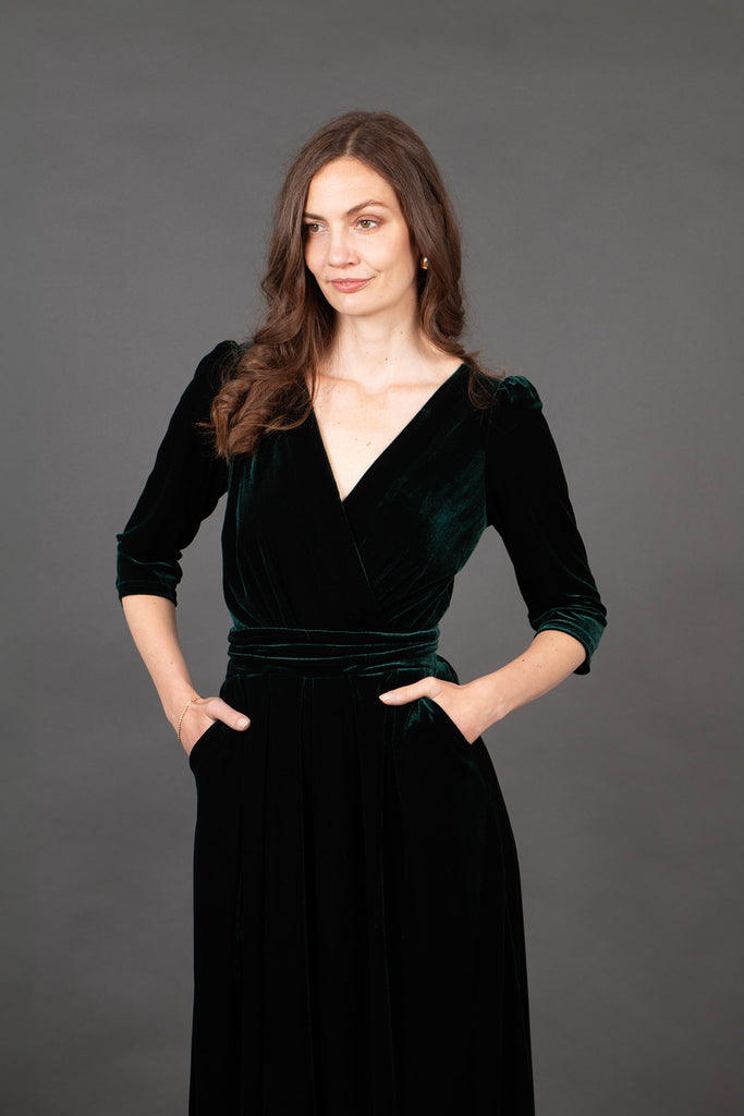 close up of the green velvet material, the model showing the v-neck line and the pockets on the jumpsuit