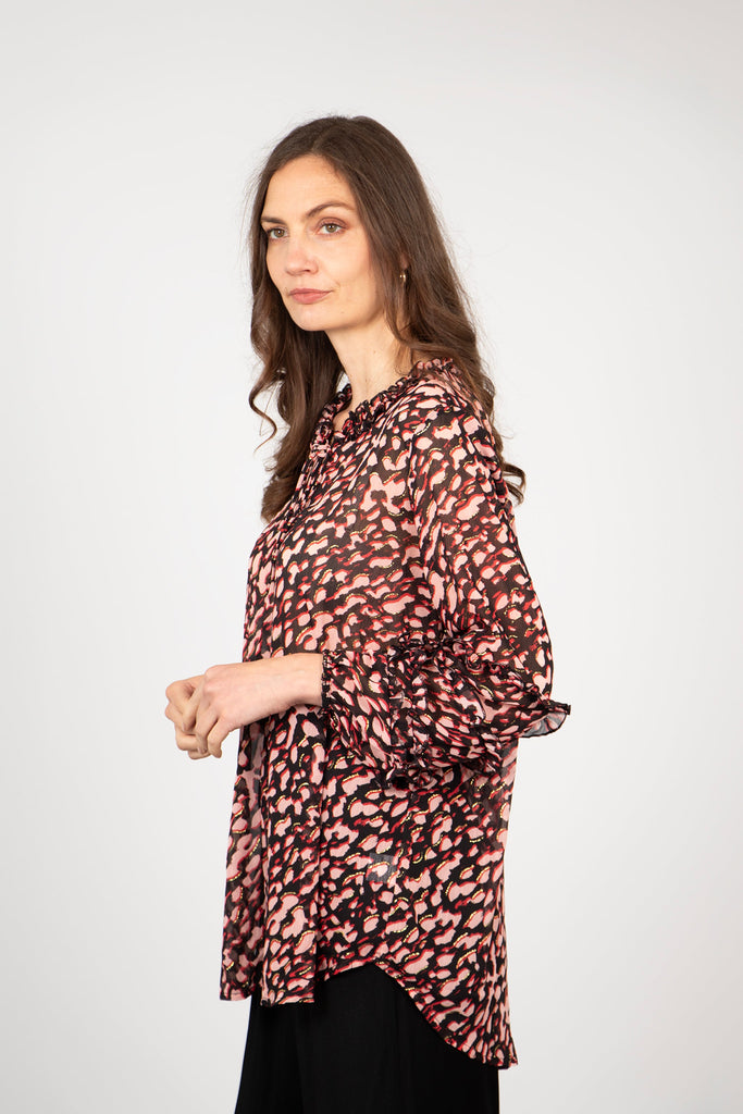 model showing the side view of the long sleeved blouse, showing the dipped hem which is longer at the back than at the front