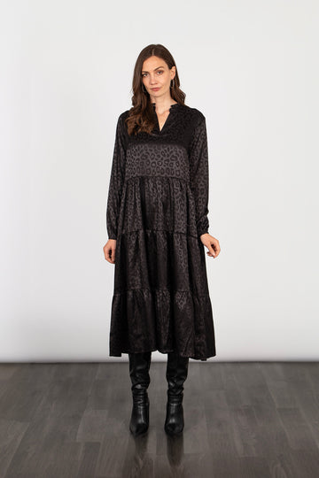 model wearing a loose fitting tiered midi dress with an all over black leopard print pattern and long sleeves