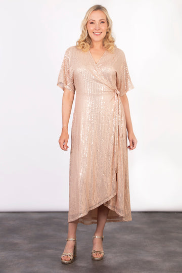 model wearing a gold midi length dipped hem sparkly sequinned wrap dress with a v-neck and waist tie fastening