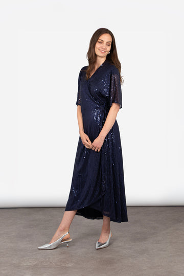 model showing the side view of the navy blue sequin wrap dress, showing the loose fitting elbow length sleeves 