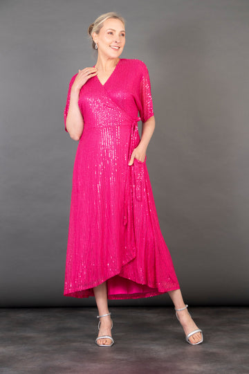 model wearing a pink midi length dipped hem sparkly sequinned wrap dress with a v-neck and waist tie fastening