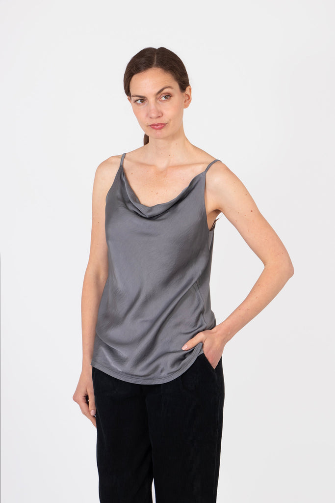 model wearing pewter grey spaghetti strap cowl neck vest top paired with black trousers