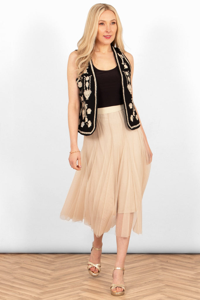 cream tulle midi skirt styled with a plain black vest top, black embroidered floral waistcoat and gold sandals.