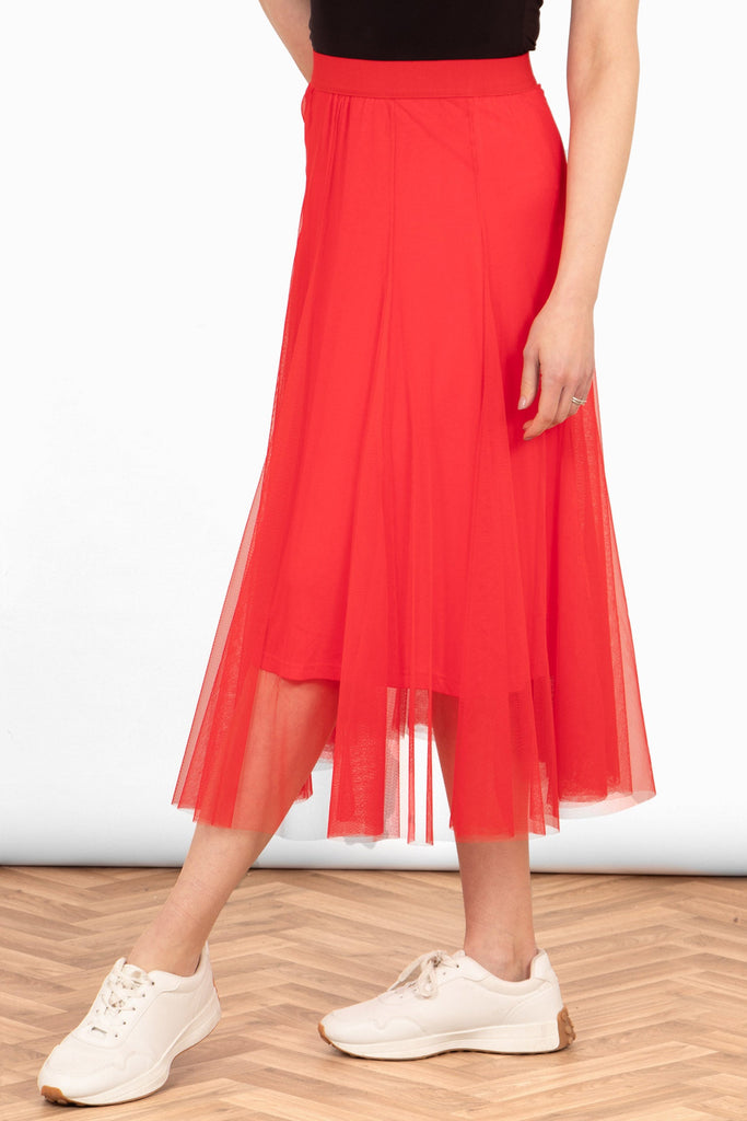 close up of the red tulle skirt, showing the underskirt layer. the tulle outer layer hangs lower than the underskirt, creating a layered appearance to the piece.