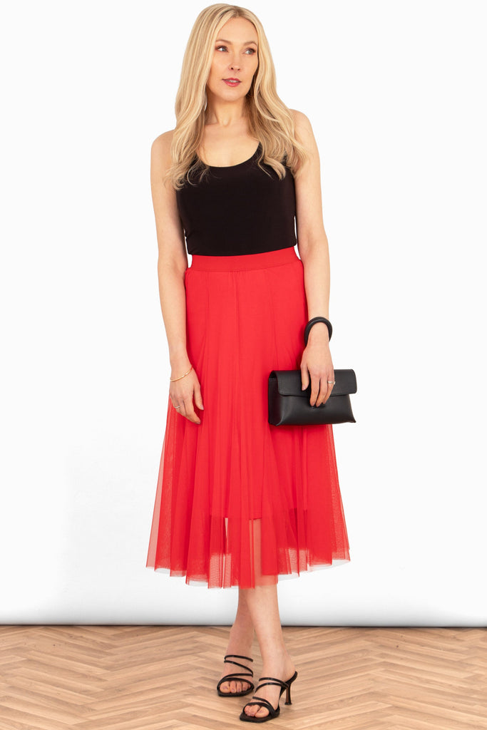 model wearing this red tulle skirt styled with a black tank top, black clutch bag and black heeled sandals showing a formal look.
