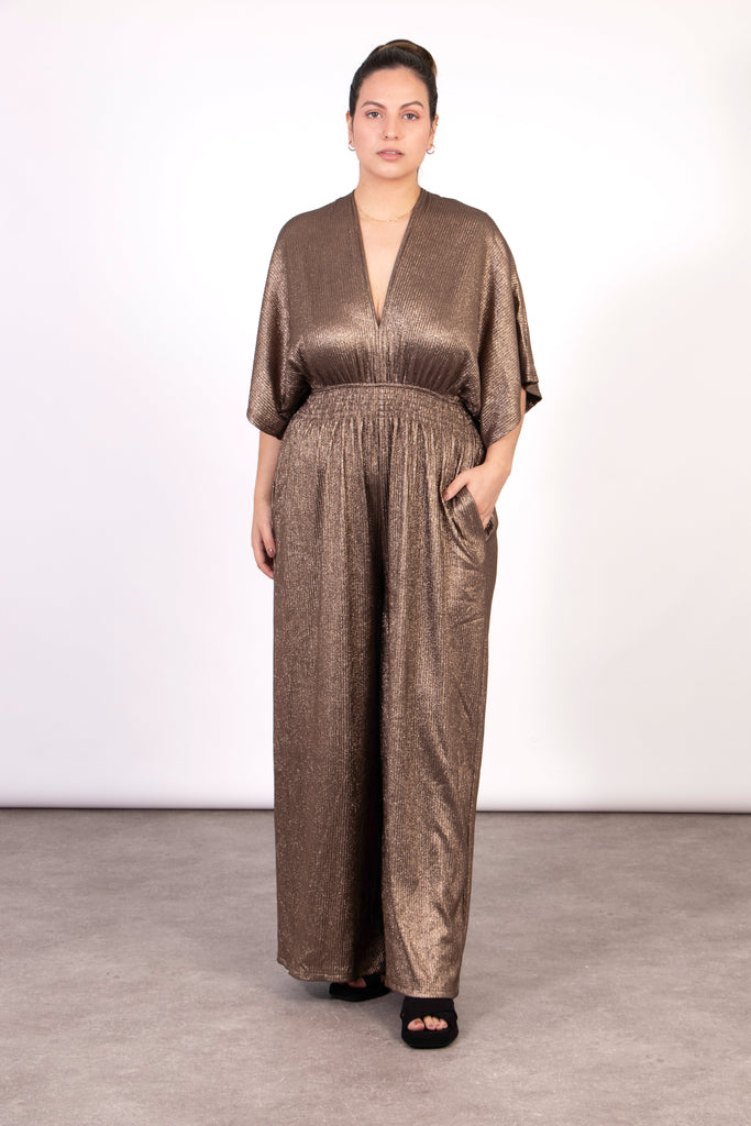 model wearing a shimmery metallic bronze wide leg jumpsuit, with short angel sleeves and a v-neck
