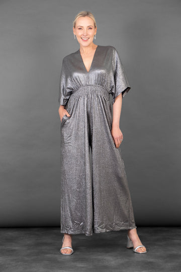 model wearing a shimmery metallic sliver wide leg jumpsuit, with short angel sleeves and a v-neck