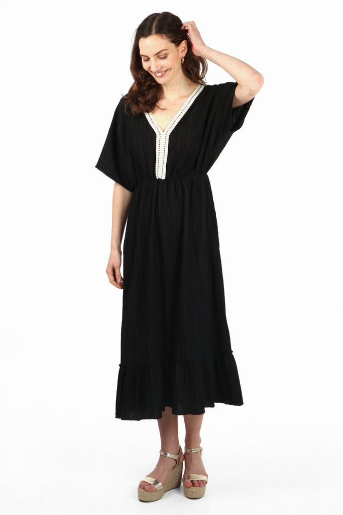 model wearing a black kaftan midi dress with a v neck and short sleeves