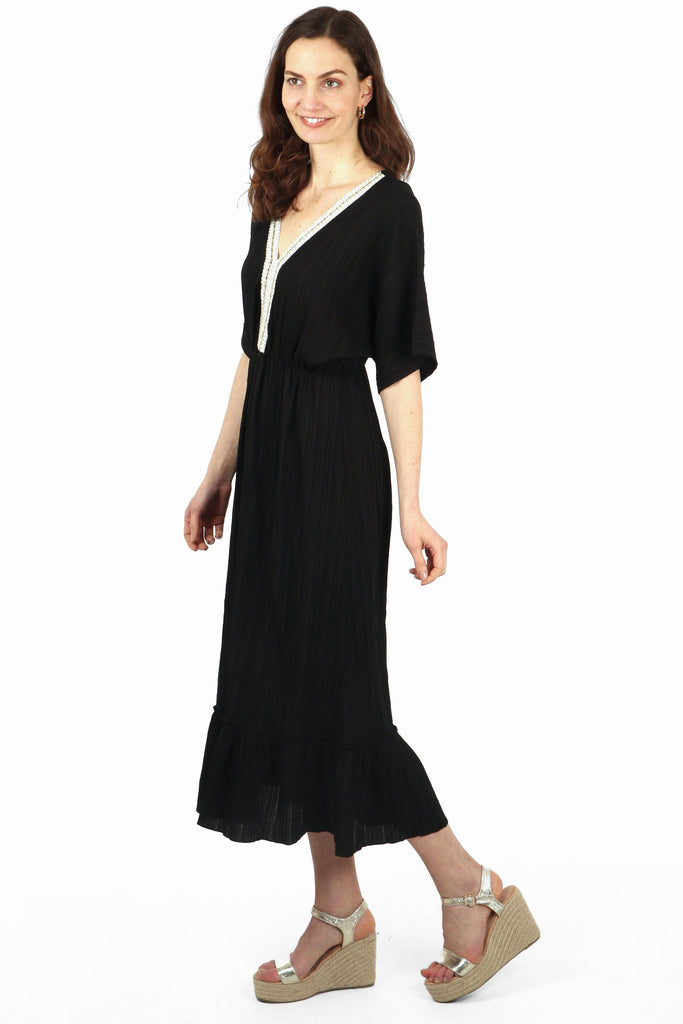 model showing the side view of the dress, highlighting the tiered trim and 3/4 sleeves