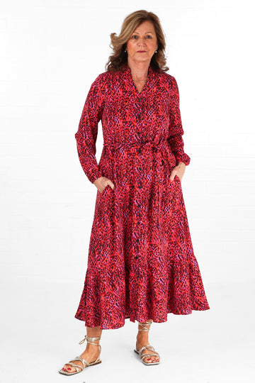 model wearing a deep pink abstract print tiered shirt dress with button down front and waist tie