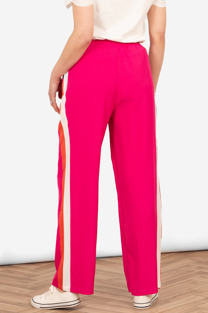 model showing the back of the pink trousers. the side stripes are visible, the back of the design is plain pink