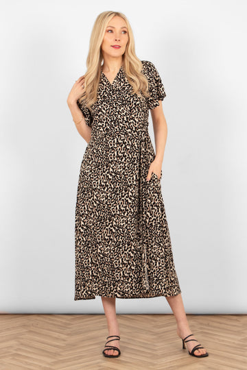 model wearing a short sleeve neutral leopard print midi wrap dress. the dress has a waist tie, v-neck and side pockets.