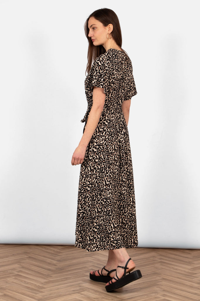 side view of the neutral leopard print wrap dress. showing the midaxi length, falling just above the ankle. the sleeves are short and loose fitting.