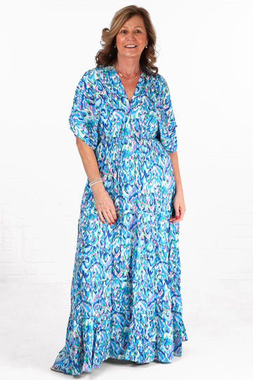 model wearing a blue abstract print maxi kaftan dress with short sleeves and a v neck