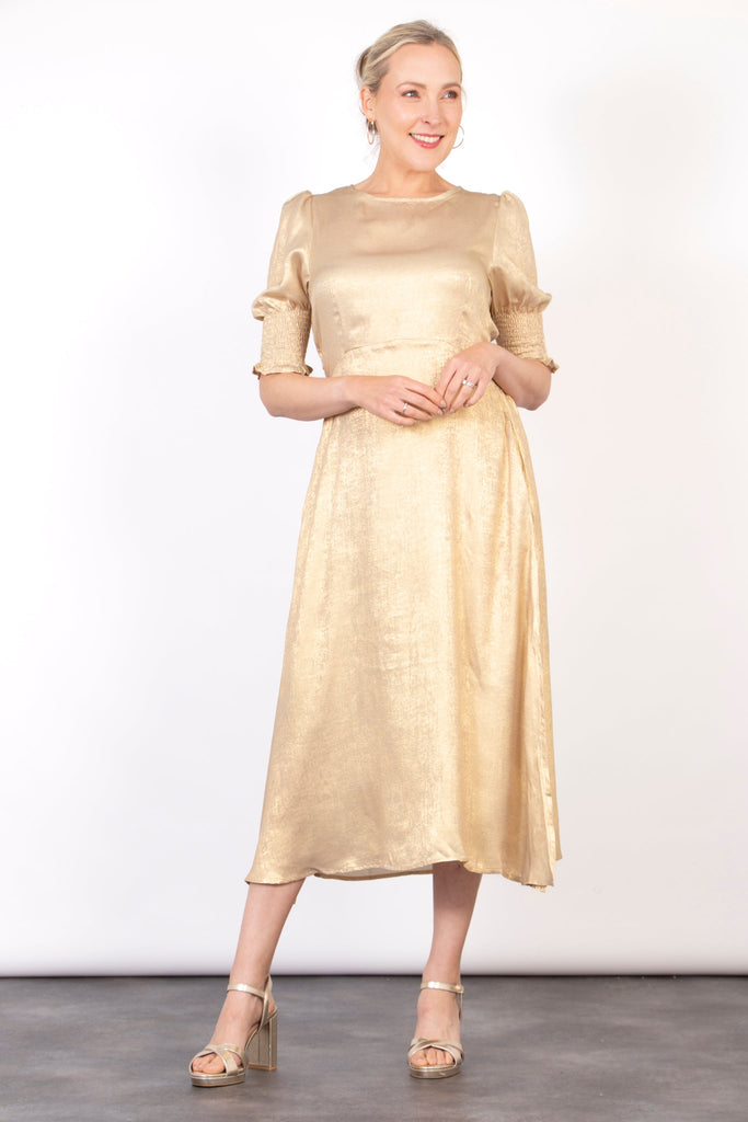 model wearing a champagne gold midi tea dress with 3/4 puff sleeves and a round neck