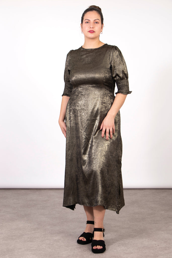 model wearing a dark metallic gold tea dress with puff sleeves and a round neck