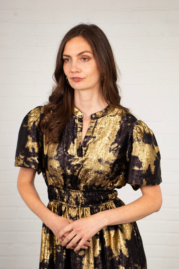 close up of the black and gold paint splash pattern on the dress, the fabric has a metallic sheen 